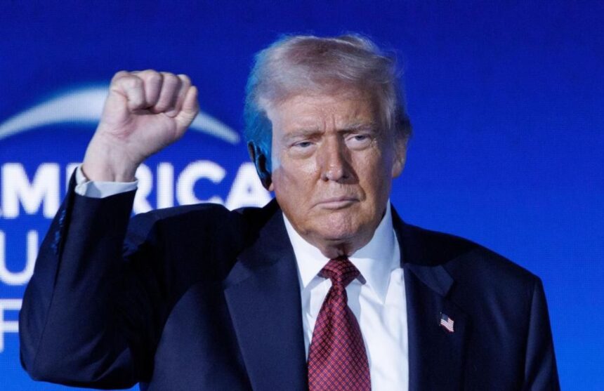Donald Trump raising his clenched right fist toward the entire audience at his conference