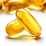 Two omega-3 capsules stacked on top of each other, with many more piled up behind them