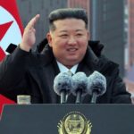 The North Korean leader speaking at a press conference in an elegant suit with many microphones around him