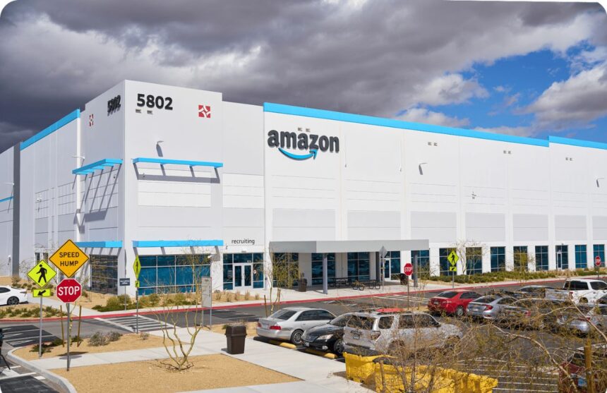 A panoramic view of a white Amazon company building with the word “Amazon” displayed above in black and blue