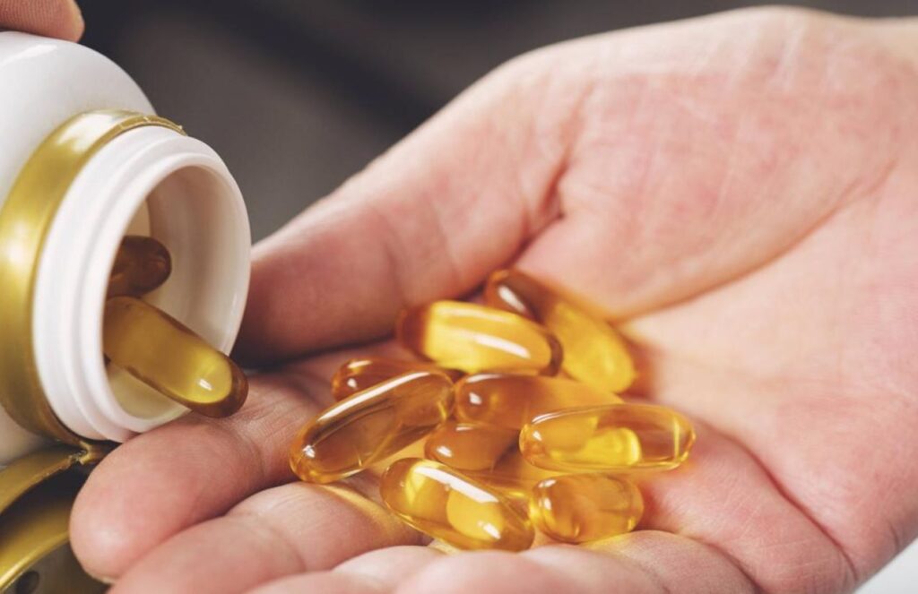 A person holding several vitamin E pills in their hand