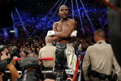 Floyd standing on the ropes of a boxing ring celebrating another victory in his career