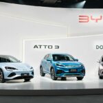 Three BYD cars displayed on platforms with the company’s name above them