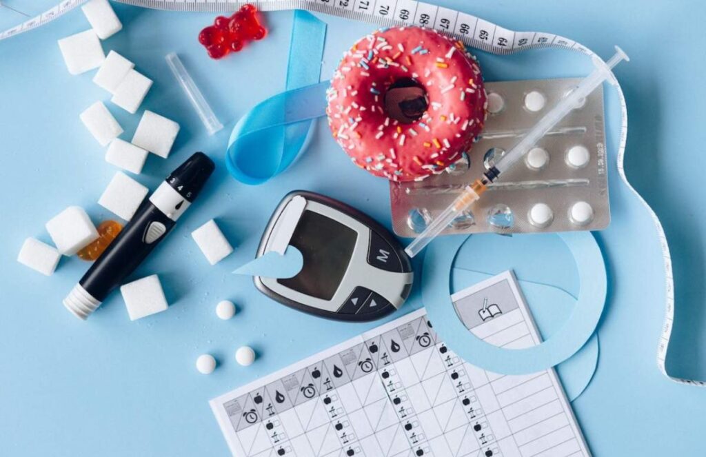 A table with medication to control diabetes, some donuts, and a glucometer