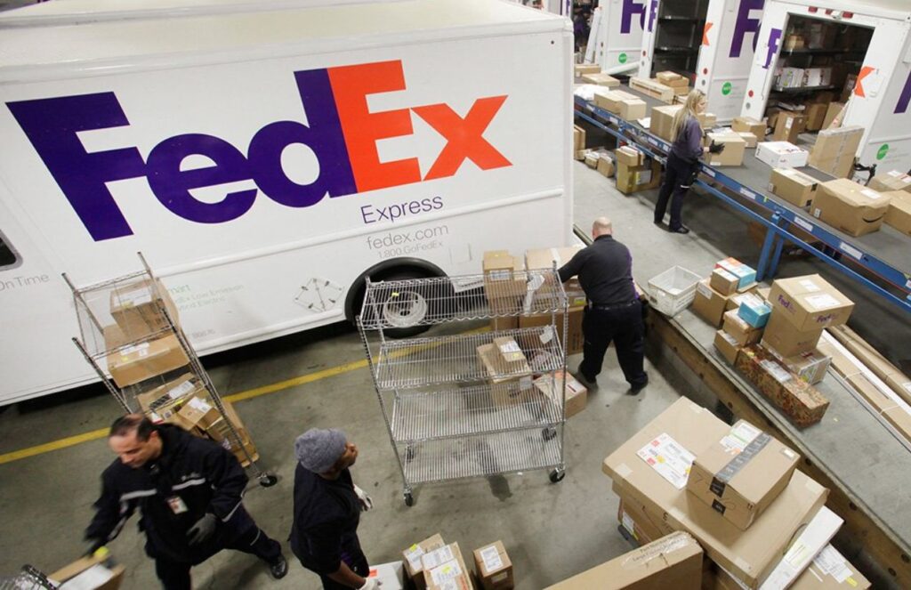 FedEx sues the United States government to recover billions in tariffs A logistics warehouse with several people loading boxes onto a FedEx truck