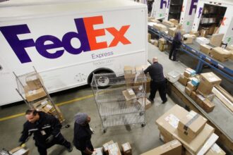 A logistics warehouse with several people loading boxes onto a FedEx truck