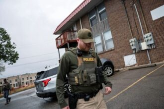 A police officer walking down a neighborhood street during a raid