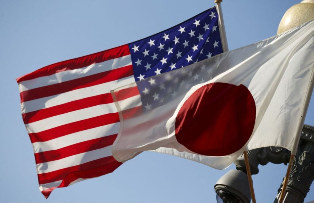 The flags of the United States and Japan, hanging from banners as the breeze blows against them