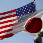The flags of the United States and Japan, hanging from banners as the breeze blows against them