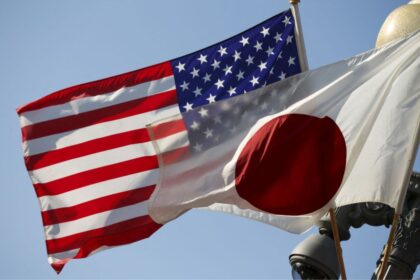 The flags of the United States and Japan, hanging from banners as the breeze blows against them