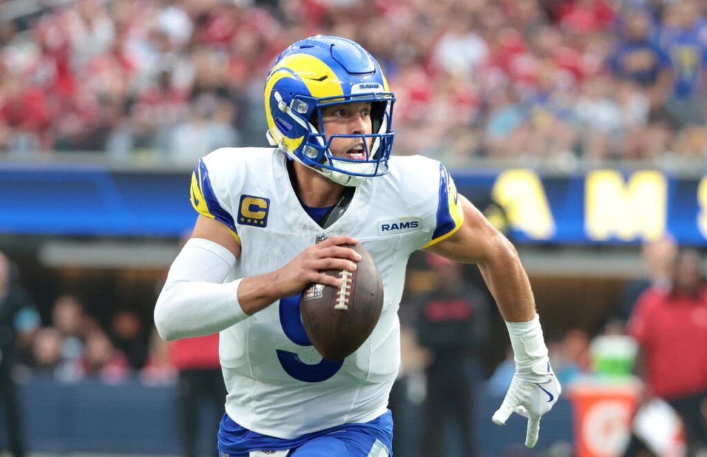 Stafford running with the ball during a game while wearing the Rams’ white uniform
