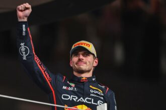 Max celebrating with a raised fist while holding one of his trophies