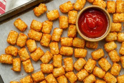 A table with diced cooked potatoes and a cup of ketchup on the side