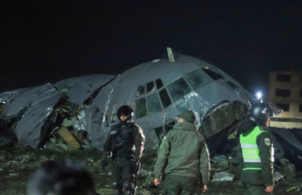 Tragedy in Bolivia: Military plane crashes near airport, leaving dozens of victims A completely destroyed airplane with several emergency service personnel surrounding the area and securing the scene