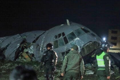 A completely destroyed airplane with several emergency service personnel surrounding the area and securing the scene