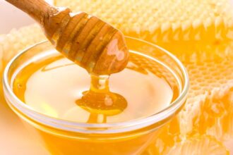 A bowl of honey with a spoon scooping some of the viscous substance