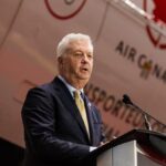 The CEO of Air Canada speaking to a large audience with a plane from the same company in the background