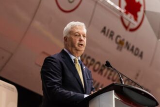 The CEO of Air Canada speaking to a large audience with a plane from the same company in the background