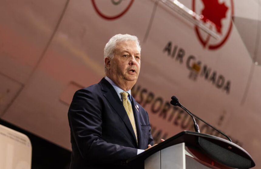 The CEO of Air Canada speaking to a large audience with a plane from the same company in the background