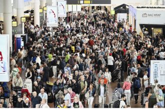 An airport crowded with people walking around, looking for their flights, and others waiting to board
