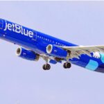 A JetBlue airplane with its characteristic royal blue color about to land at an airport
