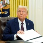 Donald Trump sitting in his office with several folders open