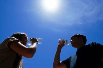 Two people drinking bottles of water after the intense heat wave hitting them