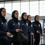 Several female players from the Iranian national soccer team with worried expressions at an airport