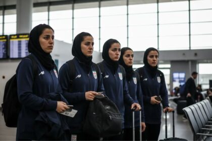 Several female players from the Iranian national soccer team with worried expressions at an airport