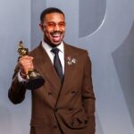 The renowned Sinners actor posing smiling and euphoric on the red carpet while holding his long-awaited award