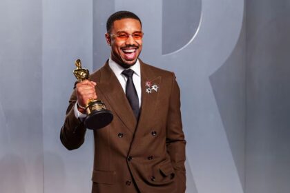 The renowned Sinners actor posing smiling and euphoric on the red carpet while holding his long-awaited award