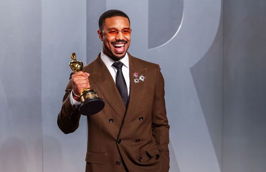 The renowned Sinners actor posing smiling and euphoric on the red carpet while holding his long-awaited award