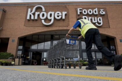 A panoramic image of a Kroger store with one of its employees organizing a row of shopping carts