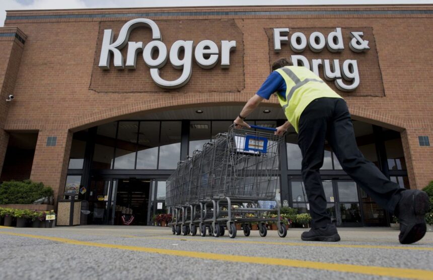 A panoramic image of a Kroger store with one of its employees organizing a row of shopping carts