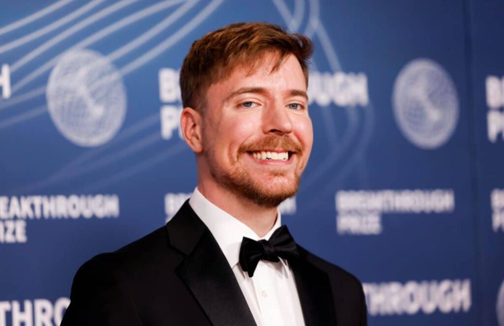 MrBeast posing in an elegant black suit on a red carpet