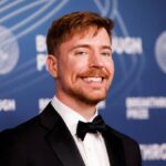 MrBeast posing in an elegant black suit on a red carpet