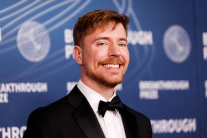 MrBeast posing in an elegant black suit on a red carpet