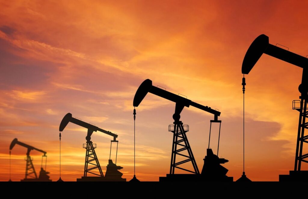 Four silhouettes of oil extraction machines in the middle of a large field