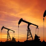 Four silhouettes of oil extraction machines in the middle of a large field