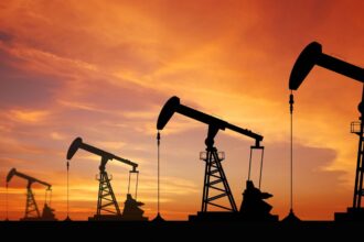 Four silhouettes of oil extraction machines in the middle of a large field