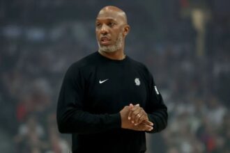 The former Portland coach applauding while walking across a basketball court