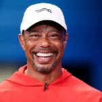 Mr. Tiger Woods wearing red and smiling widely at a golf event