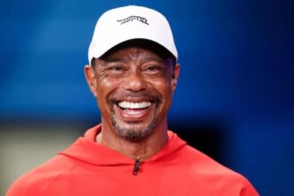 Mr. Tiger Woods wearing red and smiling widely at a golf event