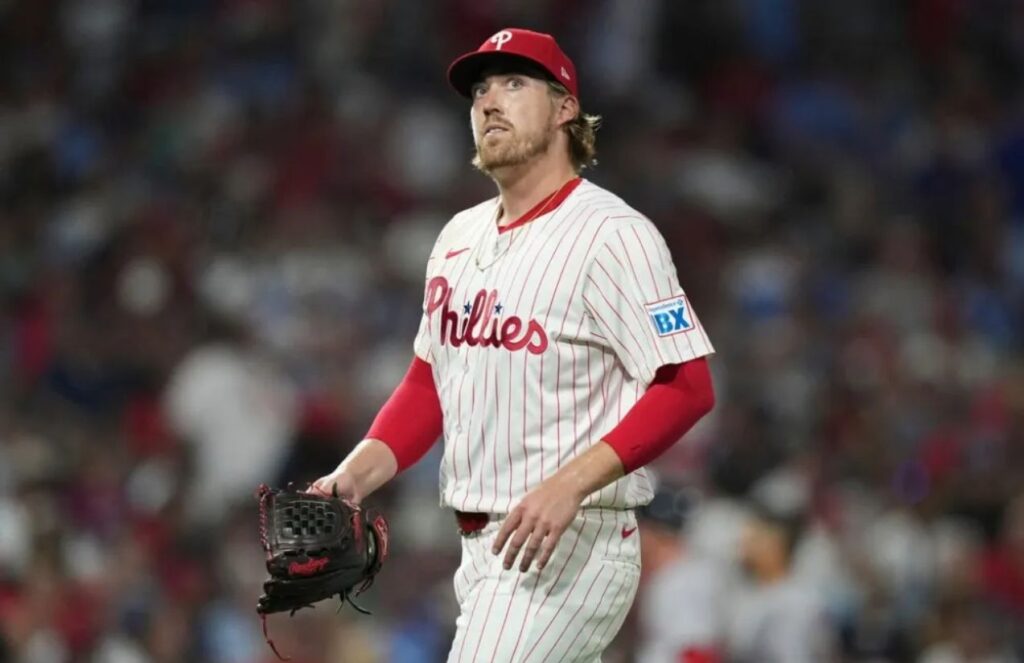 The experienced player wearing his white uniform with red sleeves walking off the field after some strong pitches