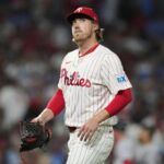 The experienced player wearing his white uniform with red sleeves walking off the field after some strong pitches