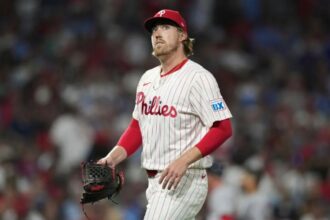 The experienced player wearing his white uniform with red sleeves walking off the field after some strong pitches