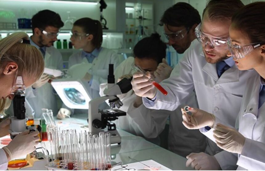 traducir Several scientists in a laboratory working with microscopes and pipettes