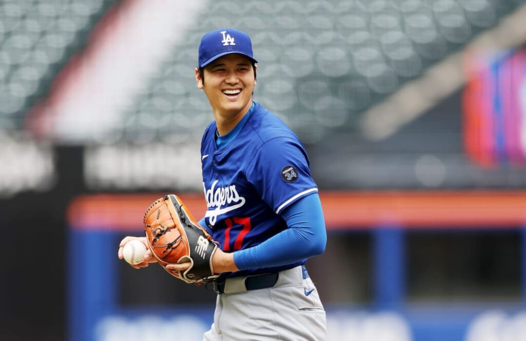 The Japanese pitcher and hitter smiling from the mound while holding a baseball with his glove