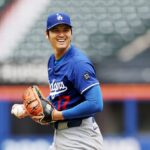 The Japanese pitcher and hitter smiling from the mound while holding a baseball with his glove