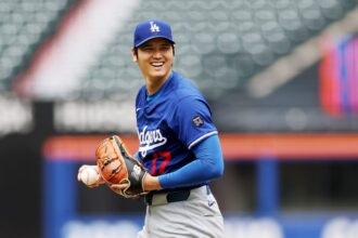 The Japanese pitcher and hitter smiling from the mound while holding a baseball with his glove
